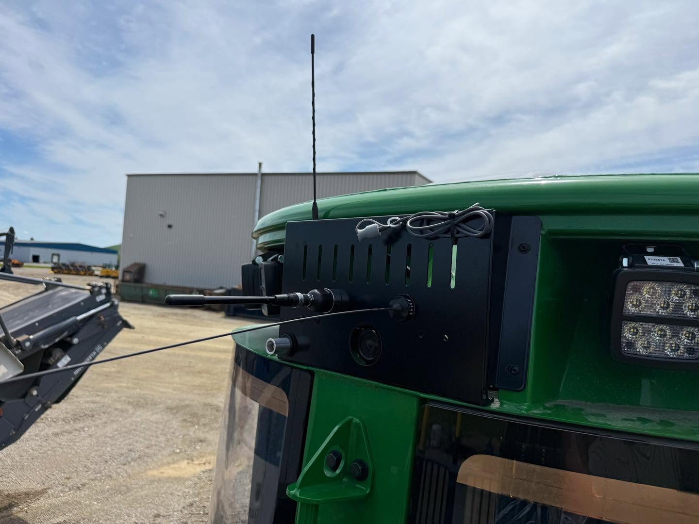Antenna mounted on the roof of a John Deere forestry forwarder against a cloudy sky
