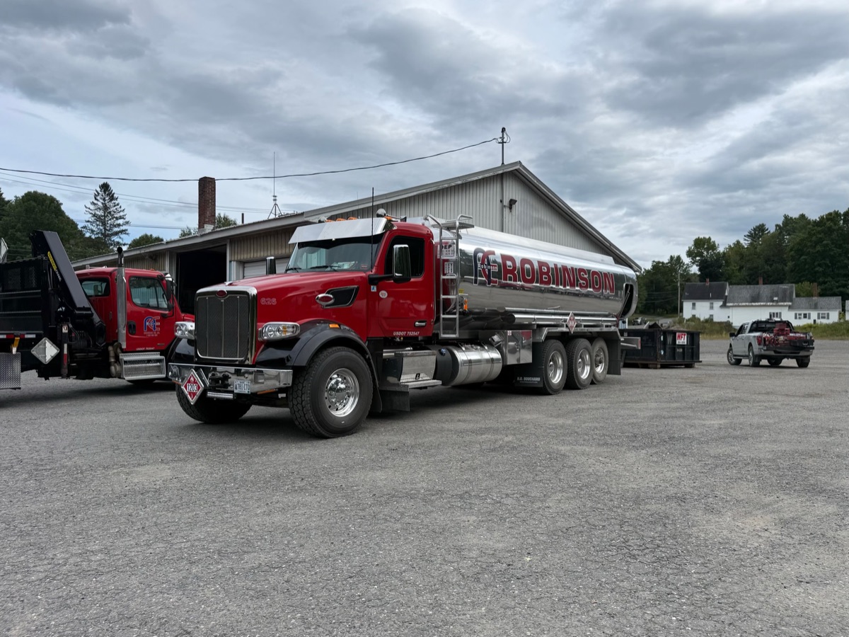 Fuel tanker truck and work trucks parked in a Maine equipment yard